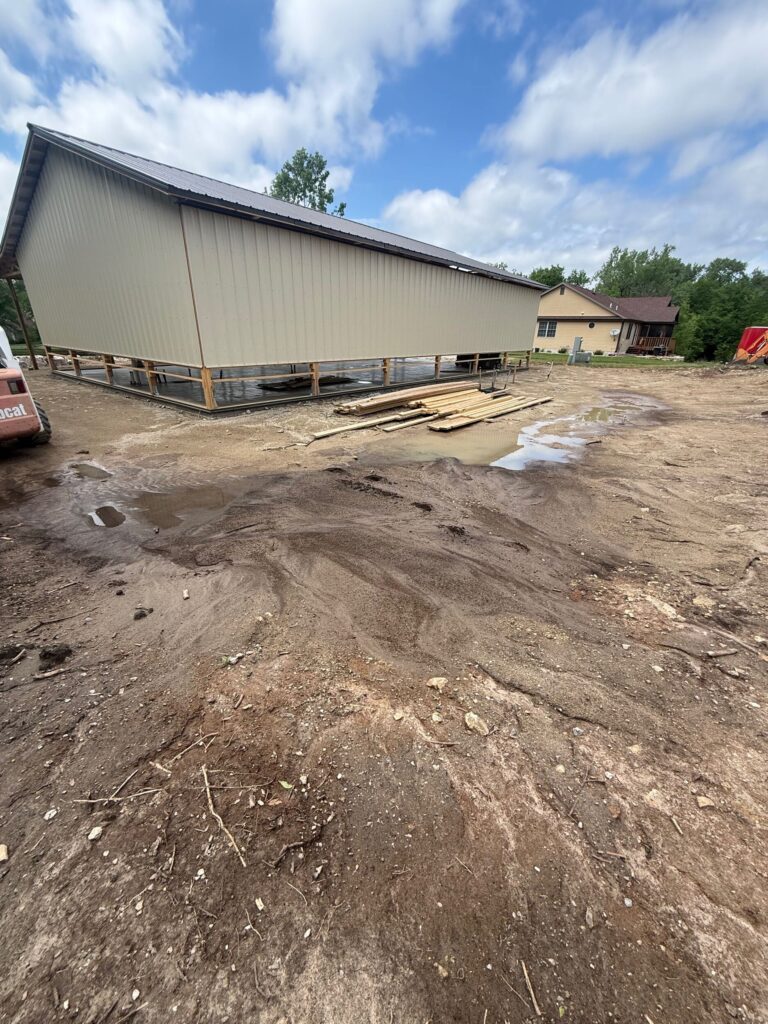 Tan post-frame pole barn under construction in Kansas with metal siding and a dark roof