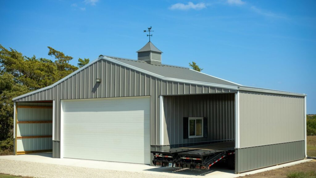 A metal barn with a large garage door and a trailer.