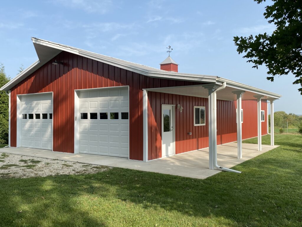 A red barn with white garage doors and a covered porch.